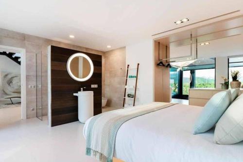 a bedroom with a large white bed and a bathroom at Montblau in Búger