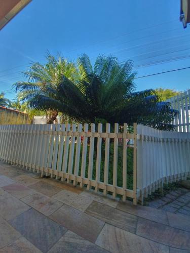 a white fence with a palm tree behind it at Pousada Pedra das Tartarugas in São Francisco do Sul