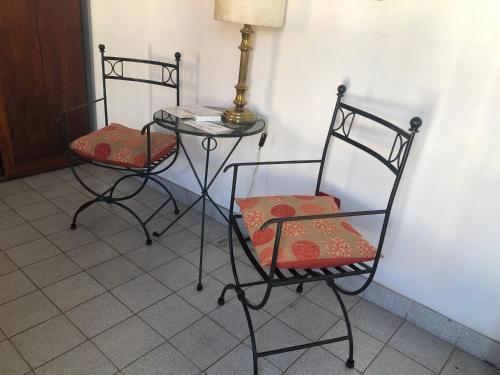 2 sillas y una mesa con una lámpara en el suelo de baldosa en Cálido apartamento en Salta