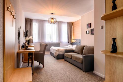pokój hotelowy z łóżkiem i kanapą w obiekcie Tailor Hotel Sport & Conference w Morągu