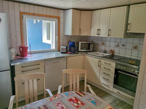 a kitchen with white cabinets and a table and chairs at Hyltenäs am Kalvsee in Kalv