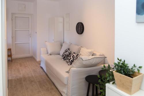 a white couch in a living room with a clock on the wall at Apartment Gordon in Mali Lošinj