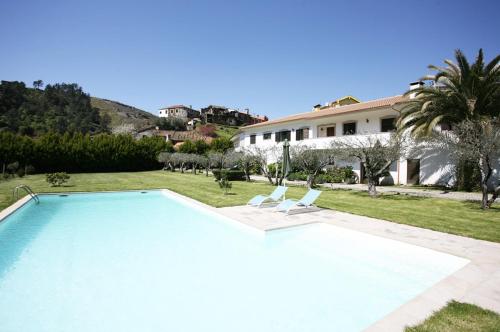 a swimming pool with two chairs and a house at Quinta Madureira in Alfolões