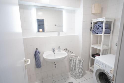 a white bathroom with a sink and a washing machine at Frühling-Studio in Dresden