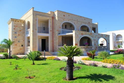 un grande edificio con palme di fronte di Villa Rosa Candida a San Foca
