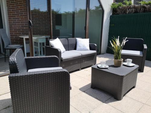 a group of wicker chairs and tables on a patio at Cabourg plage à 200m plage in Cabourg