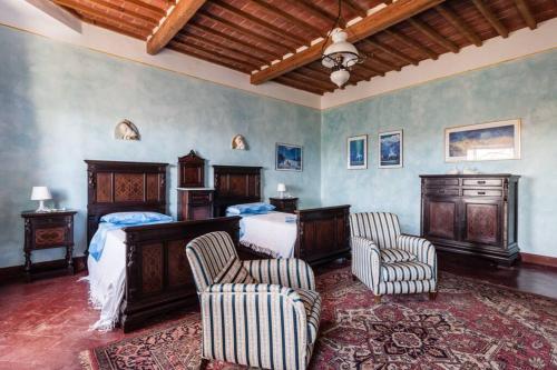 a bedroom with two beds and two chairs at Villa Ott in Crespina