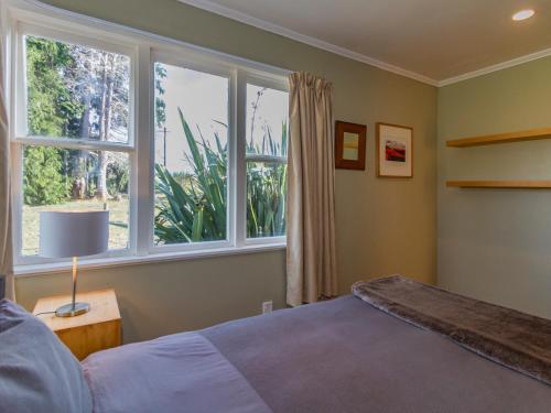 una camera da letto con un letto e una grande finestra di Snowcano Cottage - Rangataua Holiday Home a Ohakune