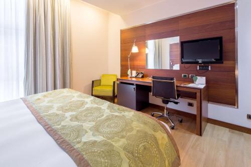 a hotel room with a bed and a desk with a computer at Best Western Premier BHR Treviso Hotel in Quinto di Treviso