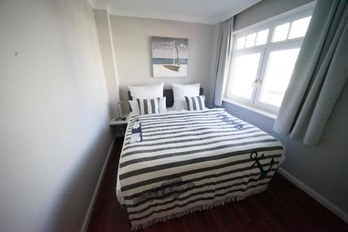 a bedroom with a bed with two chairs and a window at Residenz Strandläufer in Wenningstedt