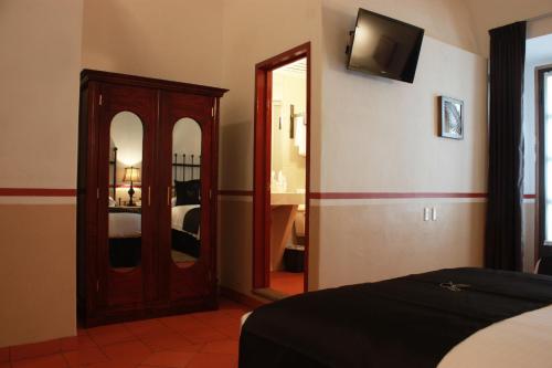 a bedroom with a mirror and a tv on the wall at Hotel de la Paz in Guanajuato