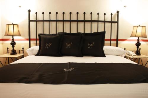 a bed with black and white sheets and pillows at Hotel de la Paz in Guanajuato