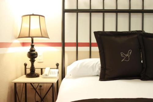 a bedroom with a bed with a lamp and a phone at Hotel de la Paz in Guanajuato