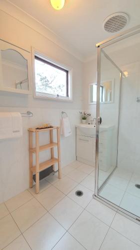 a white bathroom with a shower and a sink at Cadair Cottages in Rosebrook