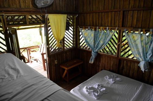 a bedroom with two beds and windows with curtains at Bella Vista Corcovado in Drake