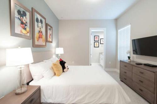 Schlafzimmer mit einem großen weißen Bett und einem Flachbild-TV in der Unterkunft New 4 BR 4 BA Villa Ground Zero to Theme Parks in Orlando