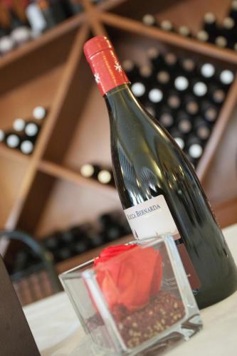 a bottle of wine sitting on a table with a rose at Hotel Ristorante Alla Botte in Portogruaro