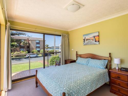 a bedroom with a bed and a large window at Champagne Court 1 in Tuncurry