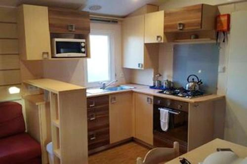 a small kitchen with a stove and a microwave at Bungalow de 3 chambres avec piscine partagee jardin amenage et wifi a Onzain in Onzain
