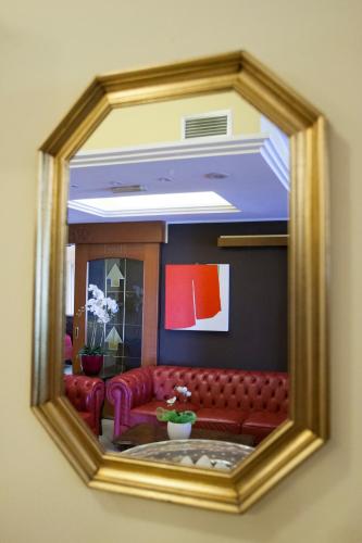 a mirror with a red couch in a living room at Hotel Ristorante Alla Botte in Portogruaro