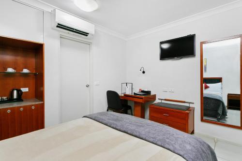 a bedroom with a bed and a desk and a mirror at Comfort Inn & Suites Burwood in Sydney