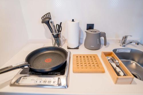 a frying pan on a stove on a kitchen counter at RESI STAY Hotel SUN CHLORELLA in Kyoto