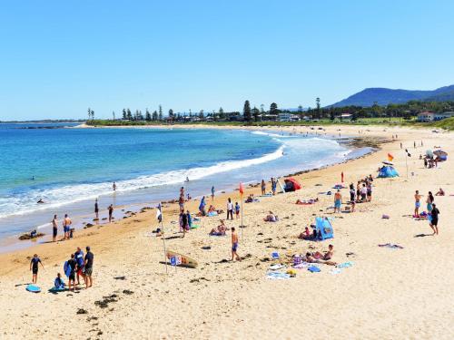 a group of people on a beach near the ocean at Sandon Point Coastal Abode in Bulli