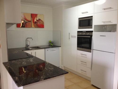 a kitchen with a refrigerator, microwave, sink and dishwasher at Pelican Cove Apartments in Gold Coast