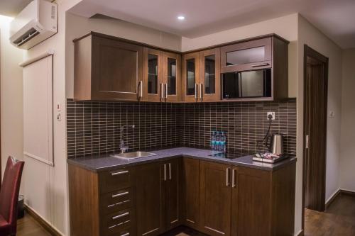 a kitchen with wooden cabinets and a sink at Al Aryam Serviced Aparthotel in Buraydah
