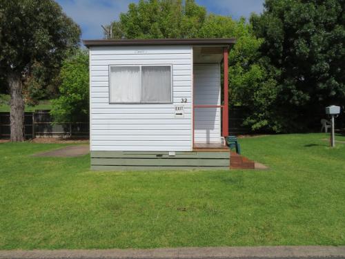 a small white shed in a field of grass at Warrnambool Motel and Holiday Park in Warrnambool