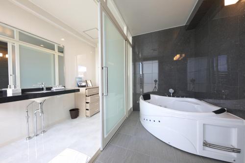 un bagno con ampia vasca bianca e lavandino di Terrace Garden Mihama Resort a Chatan