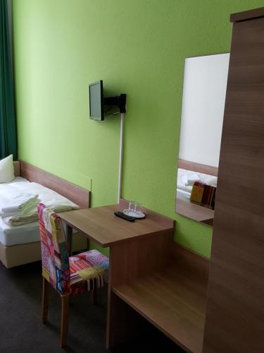 Zimmer mit einem Bett und einem Schreibtisch mit einem Spiegel in der Unterkunft Hotel Flora in Hannover