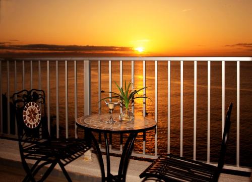 a table with wine glasses on a balcony with a sunset at Shirahama Beach 312 in Shirahama