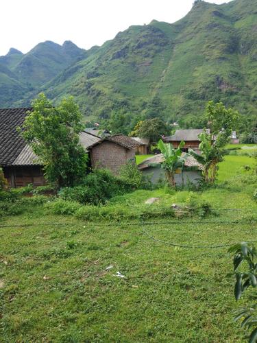 a house in a field with mountains in the background at Tày Cốc Pảng Homestay in Làng Cac