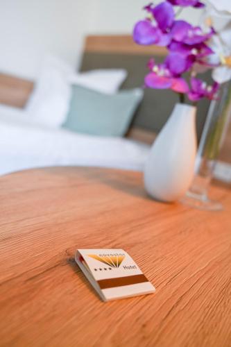 a small card on a table with a vase of flowers at Hotel Novostar in Göttingen