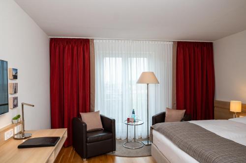 a bedroom with a bed and a desk and a chair at Hotel Stadt Freiburg in Freiburg im Breisgau