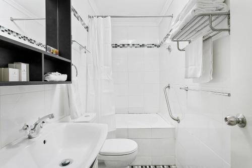 a white bathroom with a toilet and a sink at Comfort Inn & Suites Burwood in Sydney