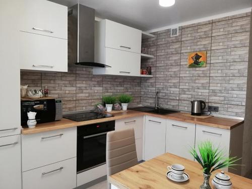 a kitchen with white cabinets and a wooden table at Helena Apartments on Mira 61 in Mogilev