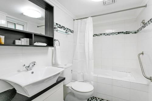 a white bathroom with a sink and a toilet at Comfort Inn & Suites Burwood in Sydney