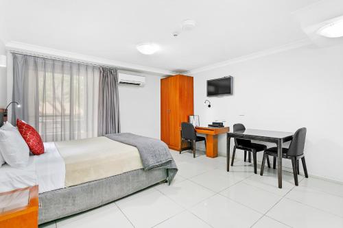 a bedroom with a bed and a desk and a table at Comfort Inn & Suites Burwood in Sydney