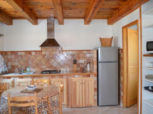 une cuisine avec une table et un réfrigérateur dans l'établissement A MANDRIA, appartements avec cuisine 30m2, patio, vue Montagnes et citadelle, 5 minutes à pied du centre ville et des rivières, à Corte