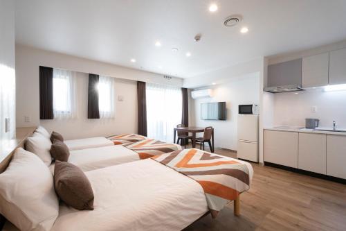 a row of beds in a room with a kitchen at Eisei Stay in Tokyo
