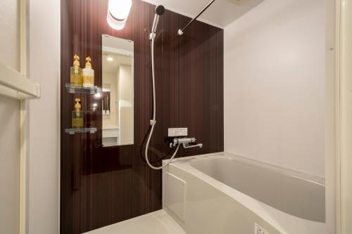 a bathroom with a bath tub and a mirror at Eisei Stay in Tokyo