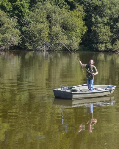 a man standing in a small boat in the water at Studio aux Sources de la Chabanne in Saint-Hilaire-les-Courbes