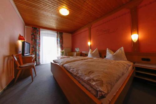 a bedroom with a large bed and a television at Gasthof-Metzgerei-Pension Schierlitz in Rimbach