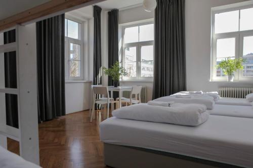 a bedroom with three beds and a table and windows at C - Punkt Hostel in Ljubljana