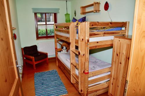 een slaapkamer met 2 stapelbedden en een stoel bij Ferienwohnung Burgerhof in Pullenreuth