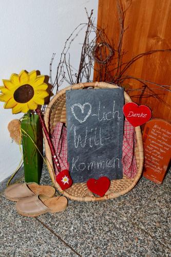a basket with a sign and a vase with a flower at Ferienwohnung Burgerhof in Pullenreuth