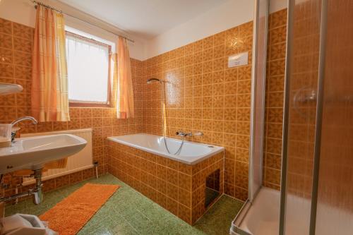 ein Bad mit einer Badewanne, einer Dusche und einem Waschbecken in der Unterkunft Gästehaus Danler in Neustift im Stubaital