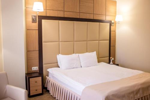 a bedroom with a white bed with a large headboard at Green Park Hotel & SPA in Truskavets